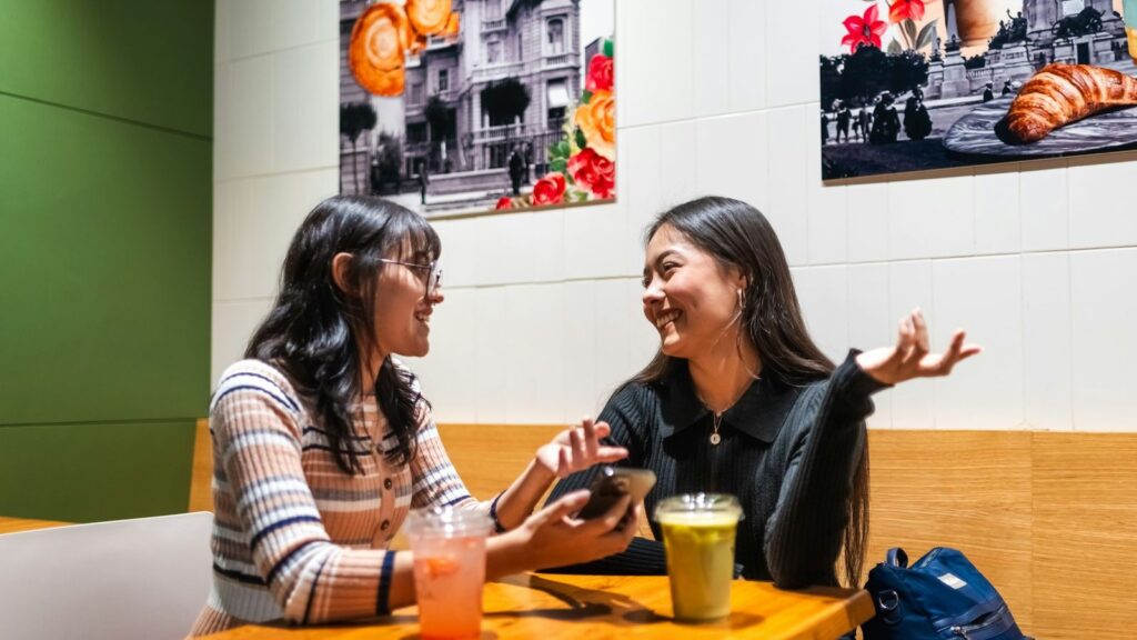 Friends chatting at a cafe table with iced soft drinks, a relaxed evening out during a PEP course