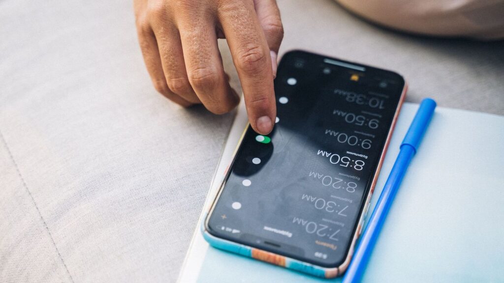 A hand holding a smartphone showing a daily alarm, used as a reminder to take a PEP dose on time