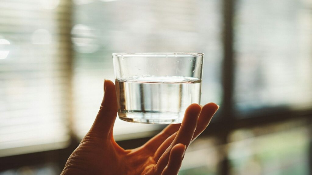 Hand holding a glass of water, ready to take a late PEP dose as soon as you remember