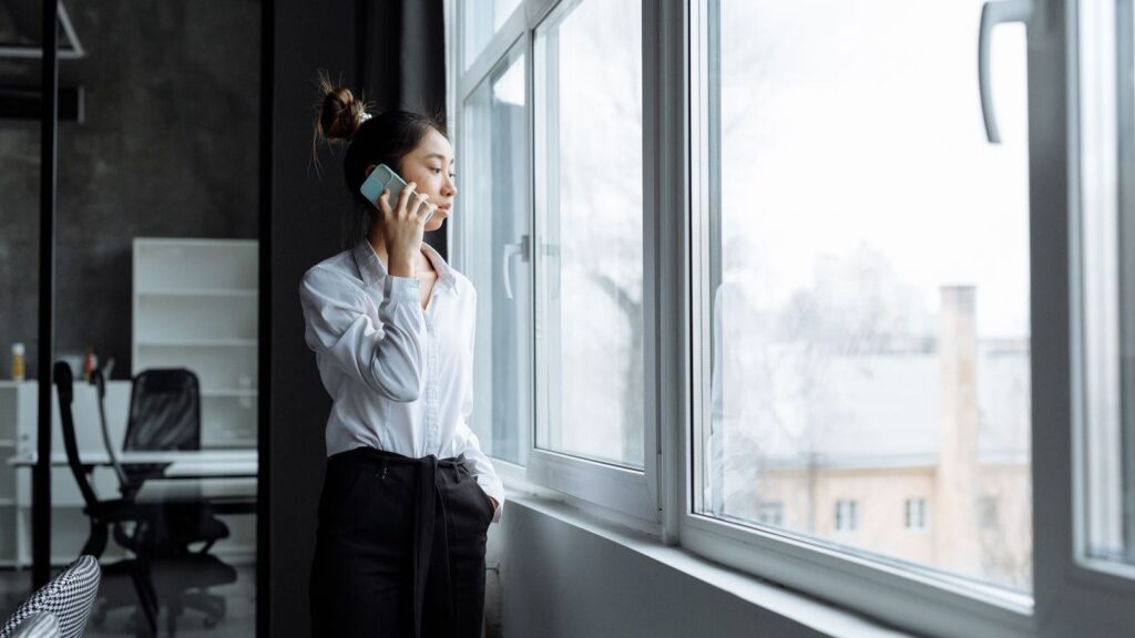 Person making a phone call by a window to arrange a confirmatory HIV test at a clinic