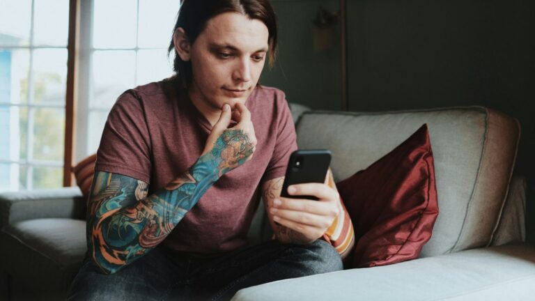 Person sitting on a sofa checking their phone, worried about HIV risk after a condom broke