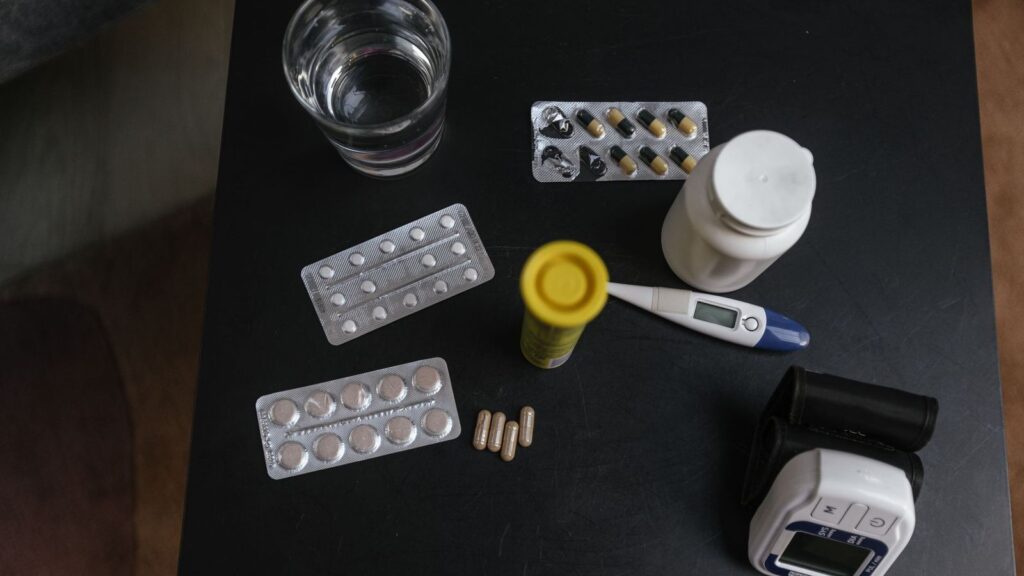 Pill bottle and a glass of water on a kitchen table, representing HIV treatment taken every day