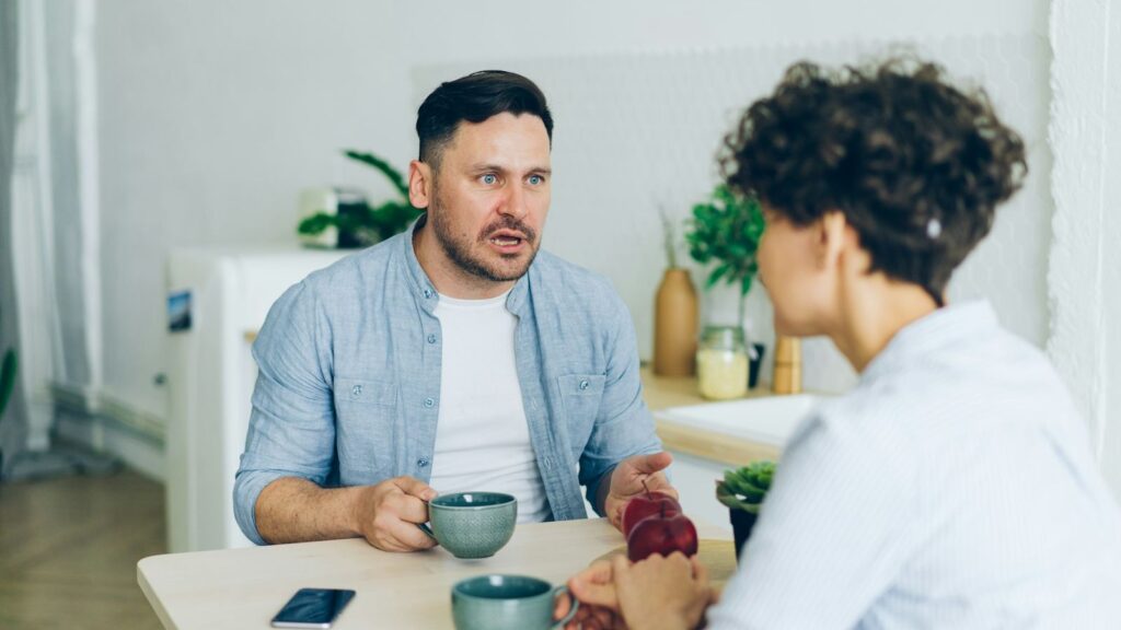 Two adults having a calm conversation at a café table about testing and sexual health