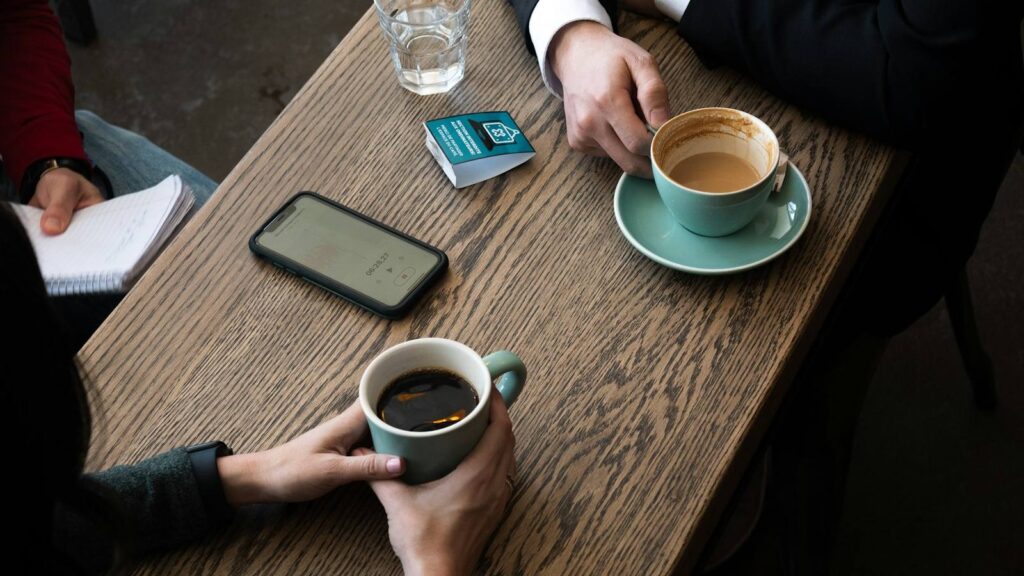 Two friends talking over coffee, sharing support while waiting for a confirmed result