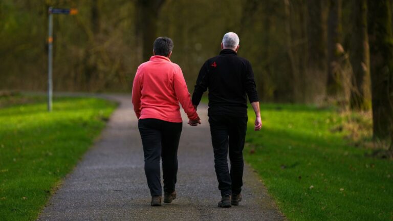 Two people holding hands on a walk in a park, a reminder that effective HIV treatment protects partners