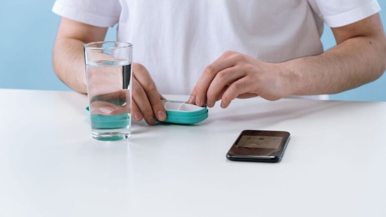 Weekly pill organiser beside a glass of water, ready for a 28-day PEP course