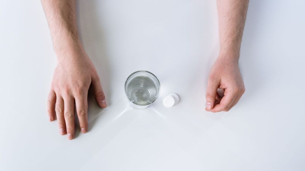White tablets beside a glass of water, representing a 28-day PEP course