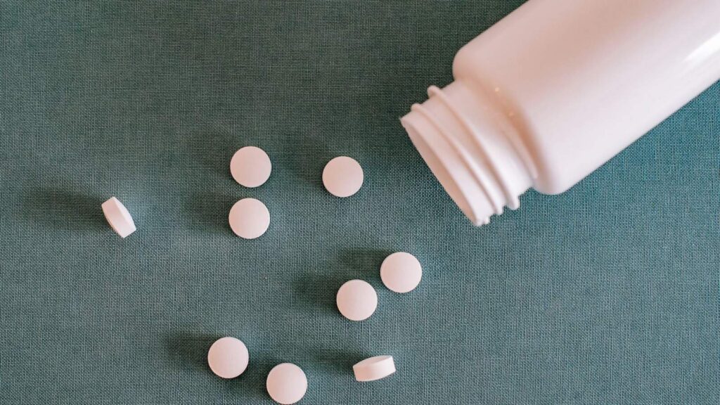 White tablets beside a plain pill bottle, representing the medicines in a PEP regimen