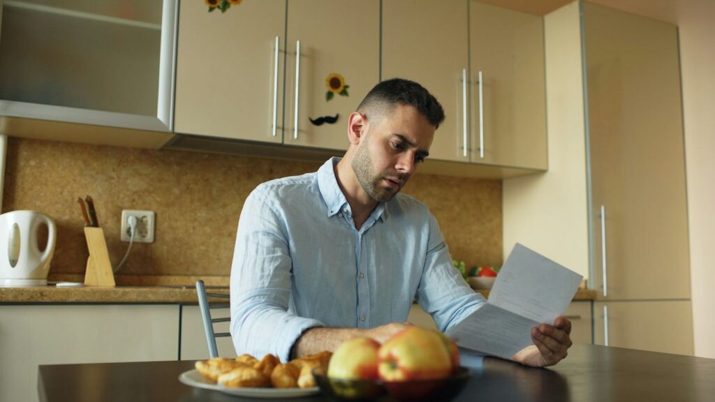 Person reading a medicine leaflet at the kitchen table to check possible PEP side effects
